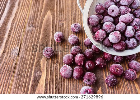 Frozen cherry berries on wooden background, selective focus