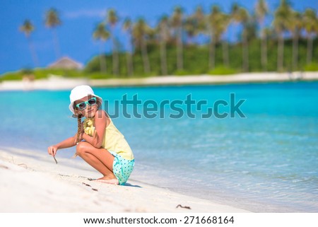 Adorable little girl drawing picture on white beach