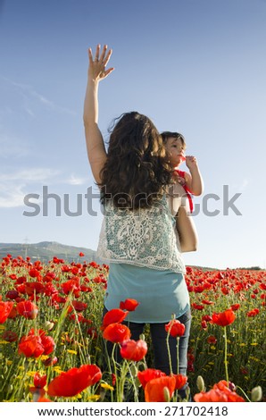 mothers back lifting baby at sunset with hand up