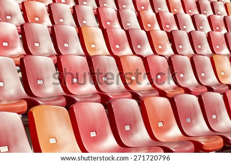 straight rows of red chairs in a sports stadium photographed at an angle