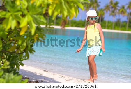 Adorable toddler girl drawing picture on white beach