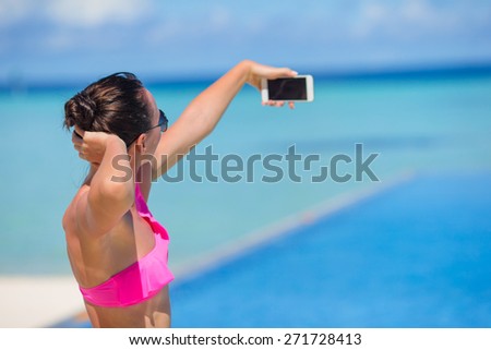 Young beautiful woman taking selfie with phone outdoors during beach vacation