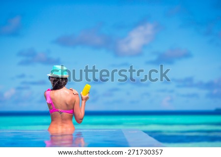 Young woman applying sun cream during beach vacation