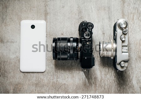 three camera retro and modern and mobile phone on a light gray background, top view