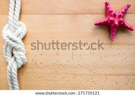 Horizontal sea travel frame with red starfish and marine knot over wooden boards