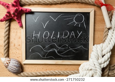 Word "Holiday" written on blackboard decorated by seashells and marine knots
