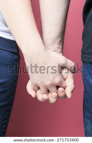 A Young Couple Holding Hands Over pink Background
