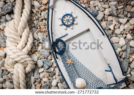 Wooden photo frame in shape of boat lying on pebbles