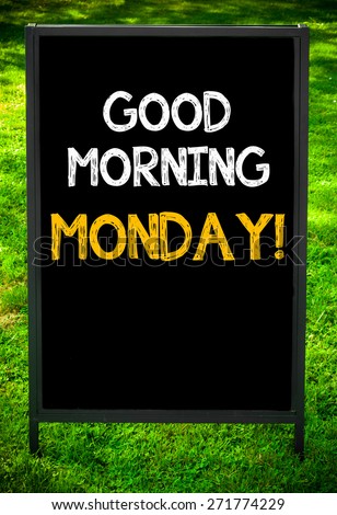 GOOD MORNING MONDAY!  message on sidewalk blackboard sign against green grass background. Copy Space available. Concept image