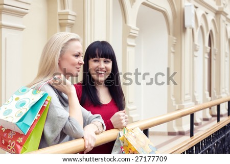 Two happy smiling women shopping with colored bags