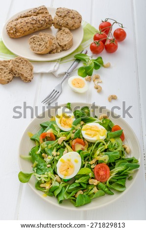Lamb's lettuce salad with roated cashews, sunflower nuts, pumpkin nuts, boiled eggs on top, healthy bread