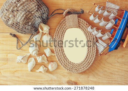 top view of vintage nautical frame from ropes, wooden boat and natural seashells on wooden table