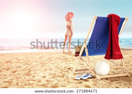 woman on sand chair with red towel and ball 
