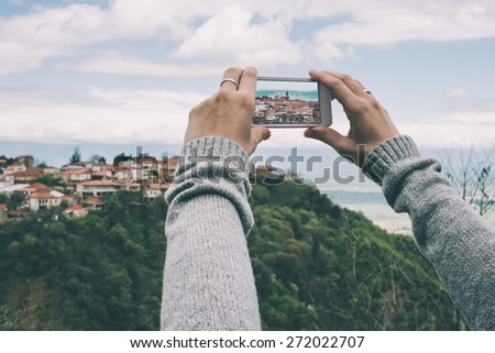 Person with smart phone makes pictures of beautiful old city from the hill. Toned picture