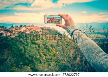 Person with smart phone makes pictures of beautiful old city from the hill. Toned picture