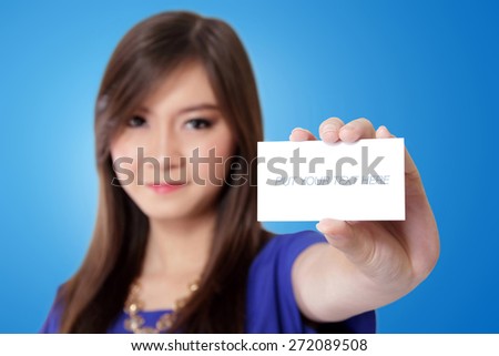 Beautiful young Asian woman showing a blank white card, on vibrant blue background