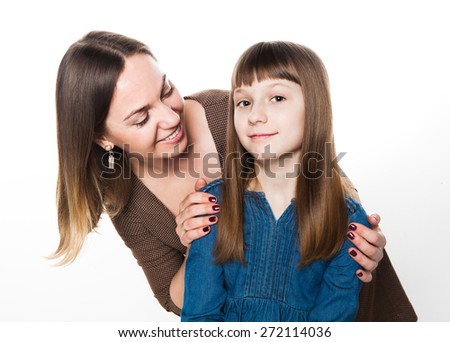 Mother embraces her daughter, looks at her and they happily smile. 