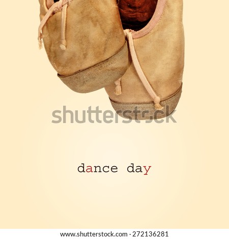 closeup of a pair of worn pointe shoes and the text dance day on a beige background, with a retro effect