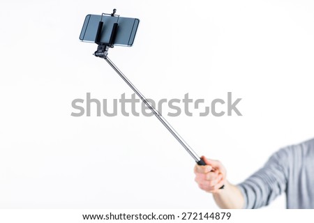 Casual man using a selfie stick shot in studio Royalty-Free Stock Photo #272144879