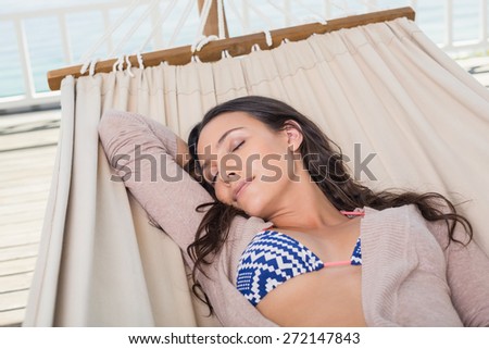 Pretty brunette relaxing on a hammock in patio