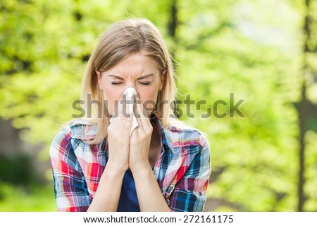 Woman with with allergy symptom blowing nose Royalty-Free Stock Photo #272161175