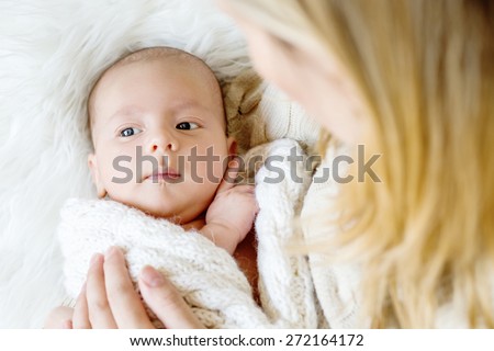 Cute newborn in mother's hands lying on the white background