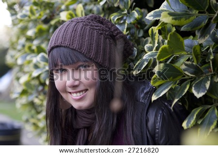 smiling girl looking from  green bush