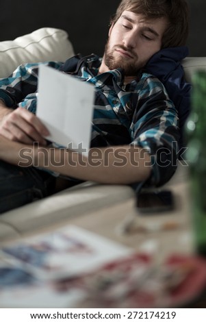 Young sad and depressed man lying on the sofa