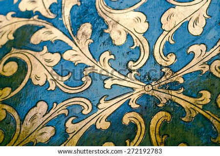 Flourish pattern. Gold leaf floral design on blue background. Old, antique surface.