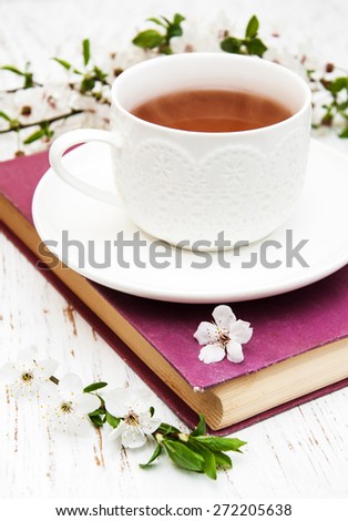 Cup of tea and cherry blossom with old book on a wooden background