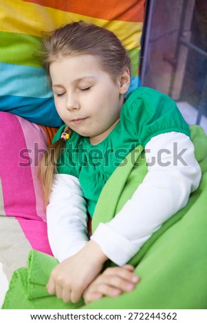 Young Caucasian girl sleeping with bright colored pillows and blanket