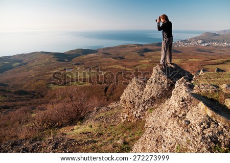 A photographer taking a photo from the top of a mountain.