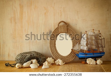 vintage nautical frame from ropes, wooden boat and natural seashells on wooden table 