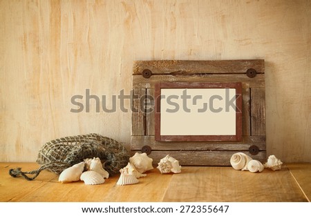 old nautical wooden frame and natural seashells on wooden table 