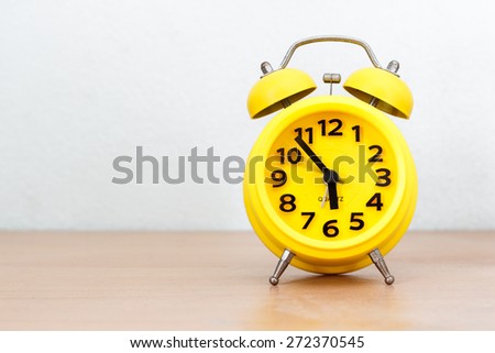 yellow alarm clock on wood table and clear background Royalty-Free Stock Photo #272370545