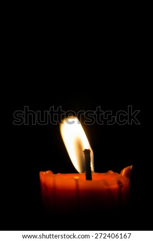 One candle burning brightly in black