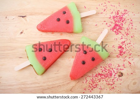watermelon shaped ice cream pops lay on wooden plate
