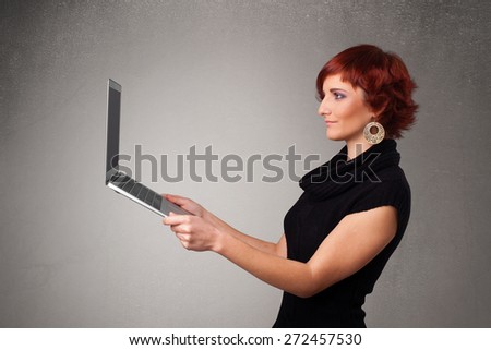Pretty young woman holding modern laptot