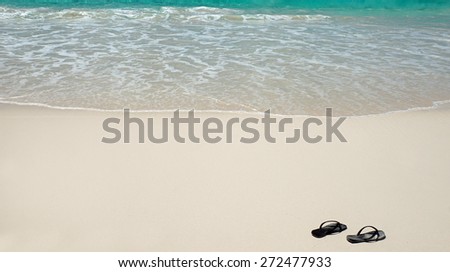 black slippers on tropical white sandy beach