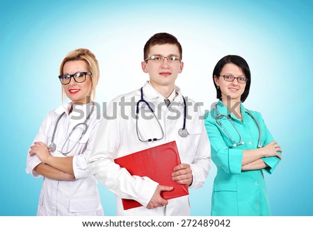 Young doctor standing with his colleagues on blue background