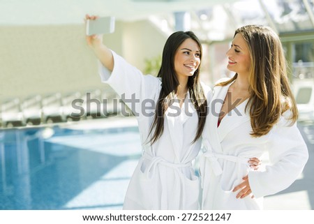 Two beautiful girls  taking a selfie next to a swimming pool