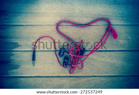 Portable audio earphones with heart Crochet on wood background, vintage color tone
