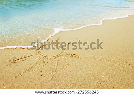 a sun drawn in the sand on the seashore 