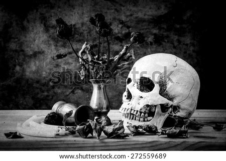 still life with skull on wooden table over grunge background
