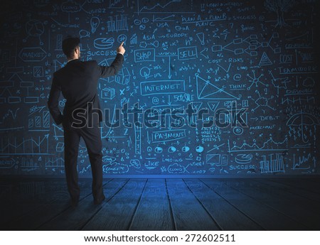 Businessman drawing business schemes on glass wall