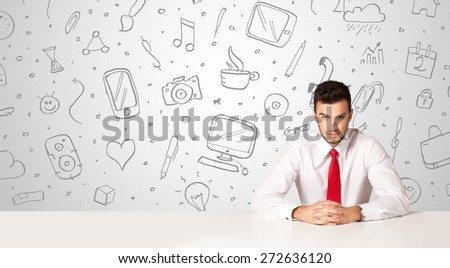 Businessman sitting at table with hand drawn media icons and symbols 