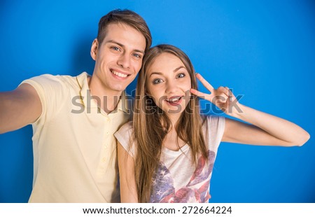 Beautiful couple having a fun together. They are making selfie on blue background.