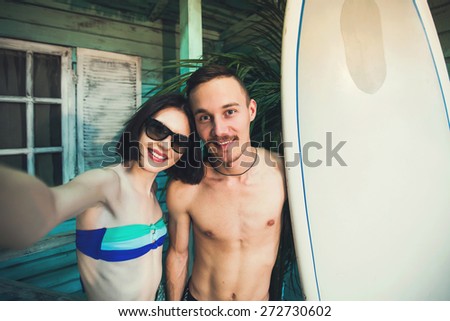 Couple of young surfers in love taking selfie picture at beach house at ocean side