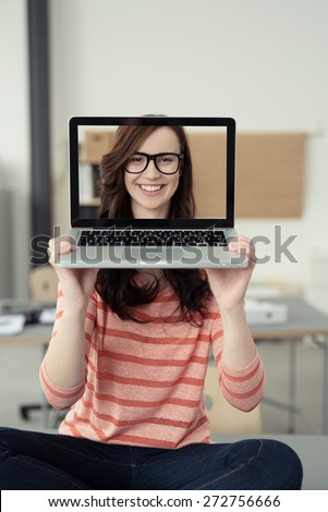 Close up Young Girl Covering her Head with Laptop Computer with her Pretty Smiling Face on the Screen