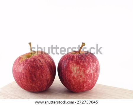 close-up two red apples with water droplets on corner of wooden kitchen table isolated on white background, round shape fruit used as dessert or ingredients of salad or making cider and juice